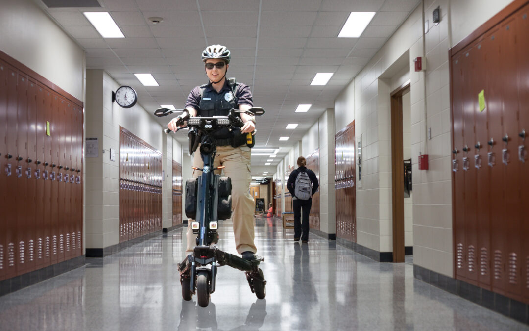 Police scooter officer riding on a college campus hallway