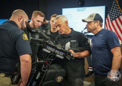 Group of officers huddled around a Fargo Police motorized bike during a briefing examining its mounted equipment as one man explains