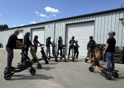 Group of people wearing helmets standing with electric scooters outside a metal warehouse